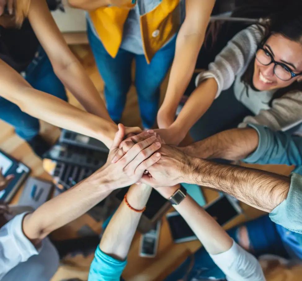 Équipe de collègues joignant leurs mains en signe de collaboration et d’unité, symbolisant la cohésion et le travail d’équipe en entreprise.